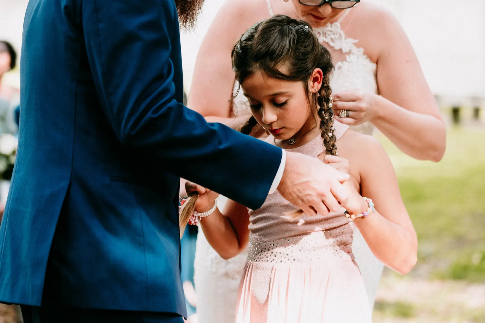 Girl touching her new necklace, the groom's hand on her shoulder