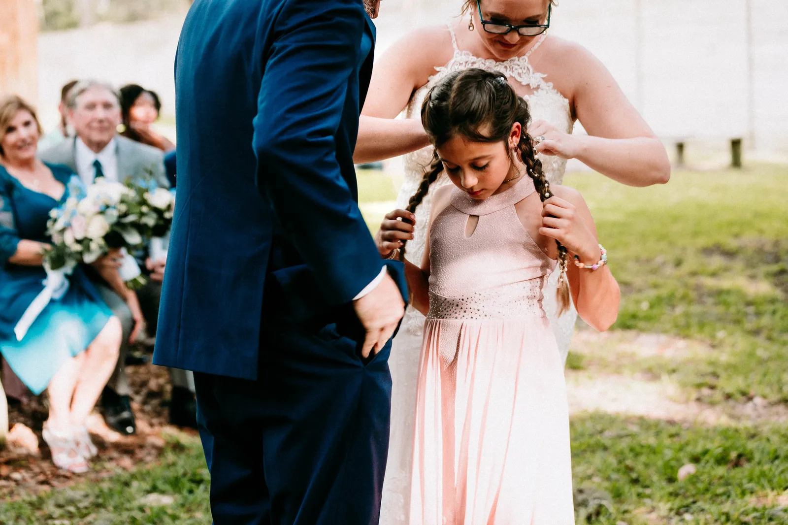 Girl holding her braids aside while the bride fastens her necklace