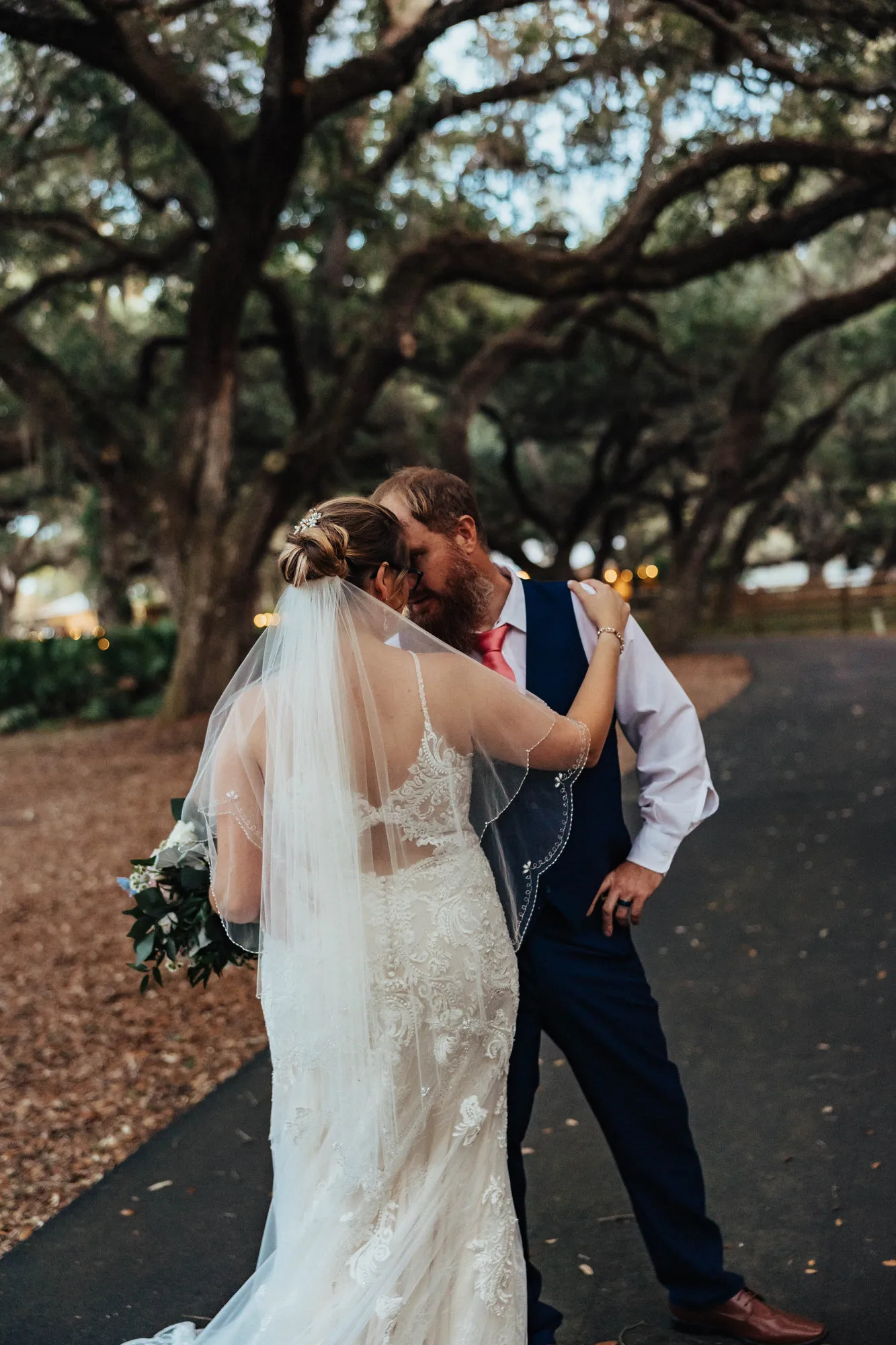 Bride and groom nose to nose on the oak-lined drive