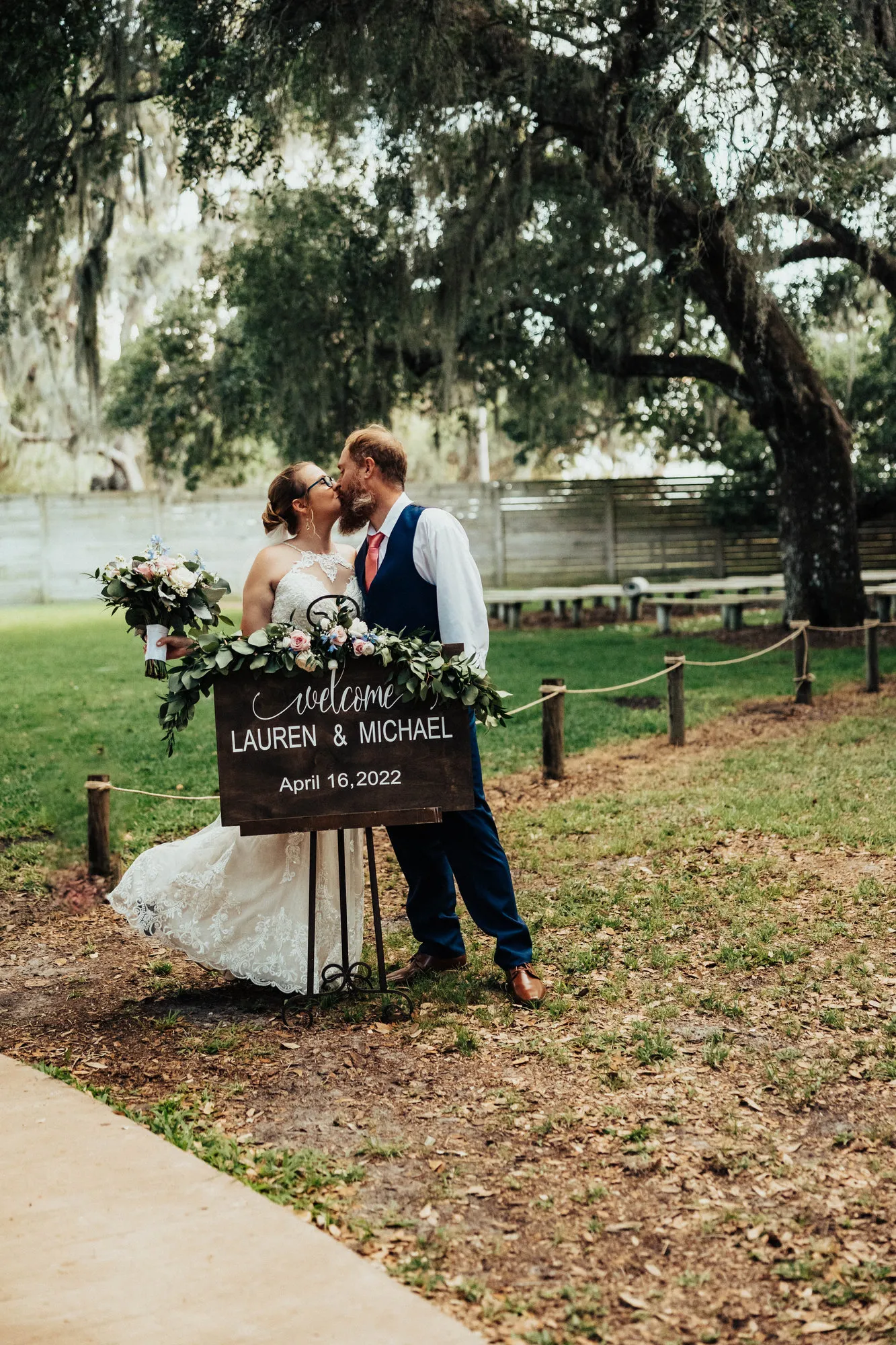 Bride and groom kissing beside their welcome sign