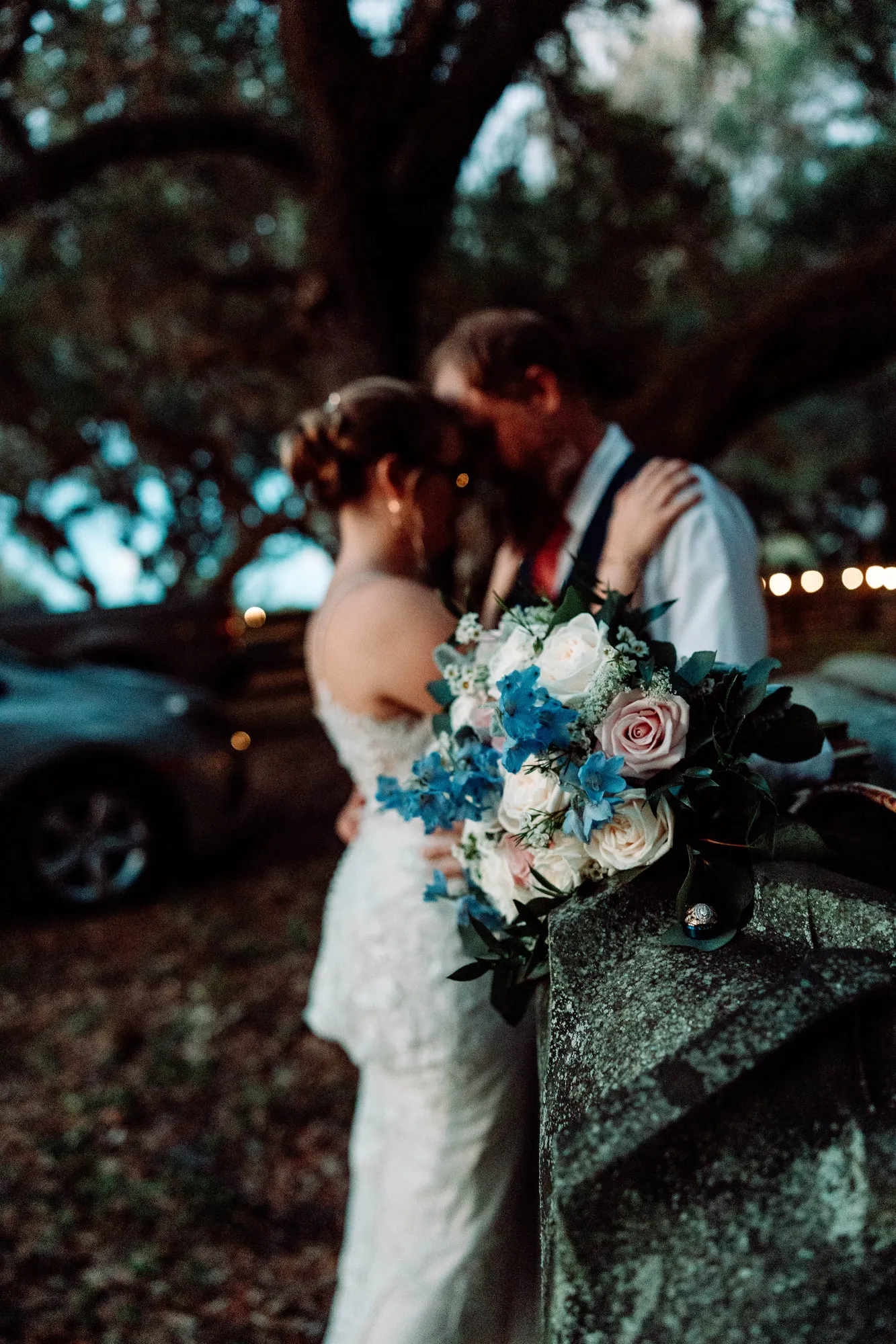 Groom kissing the bride's forehead, her bouquet on the tractor in the foreground