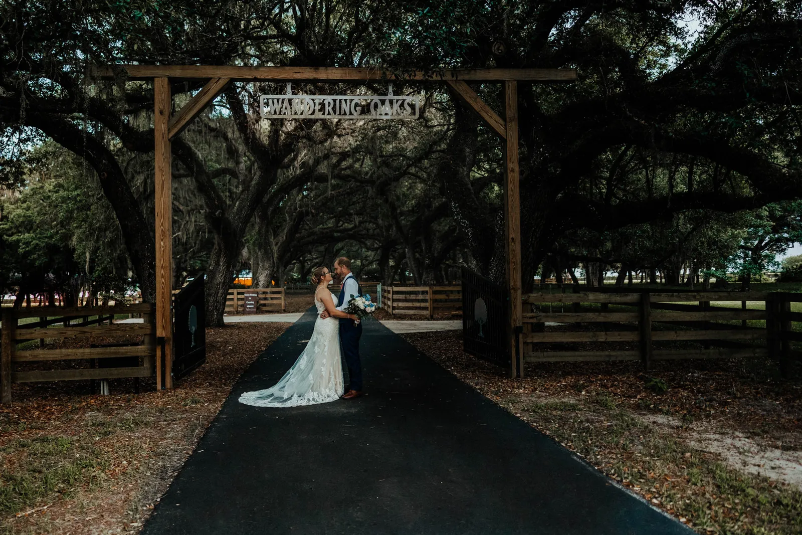 Bride and groom kissing under the Wandering Oaks entrance arch