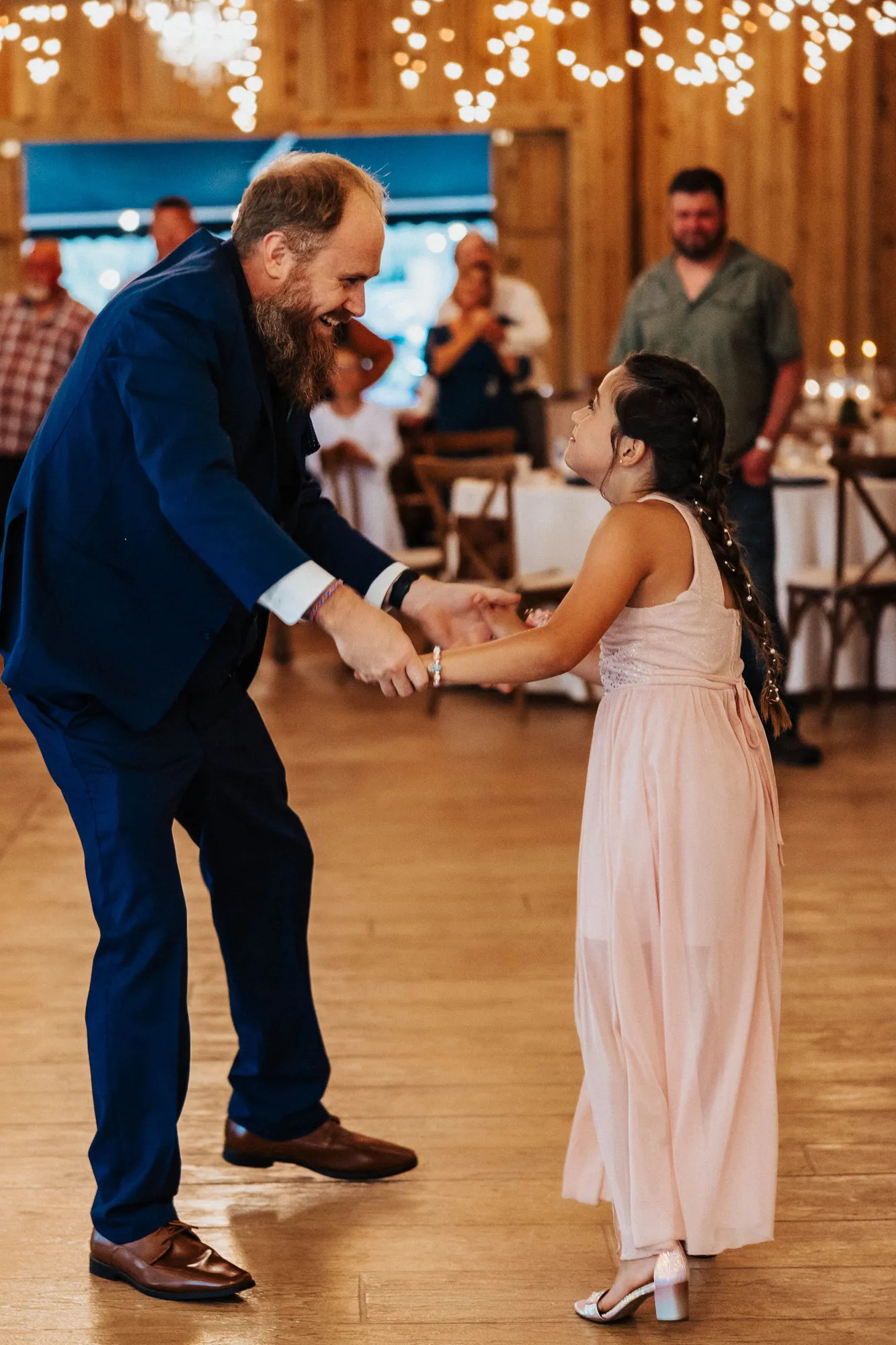 Groom and the girl in pink holding hands as they dance