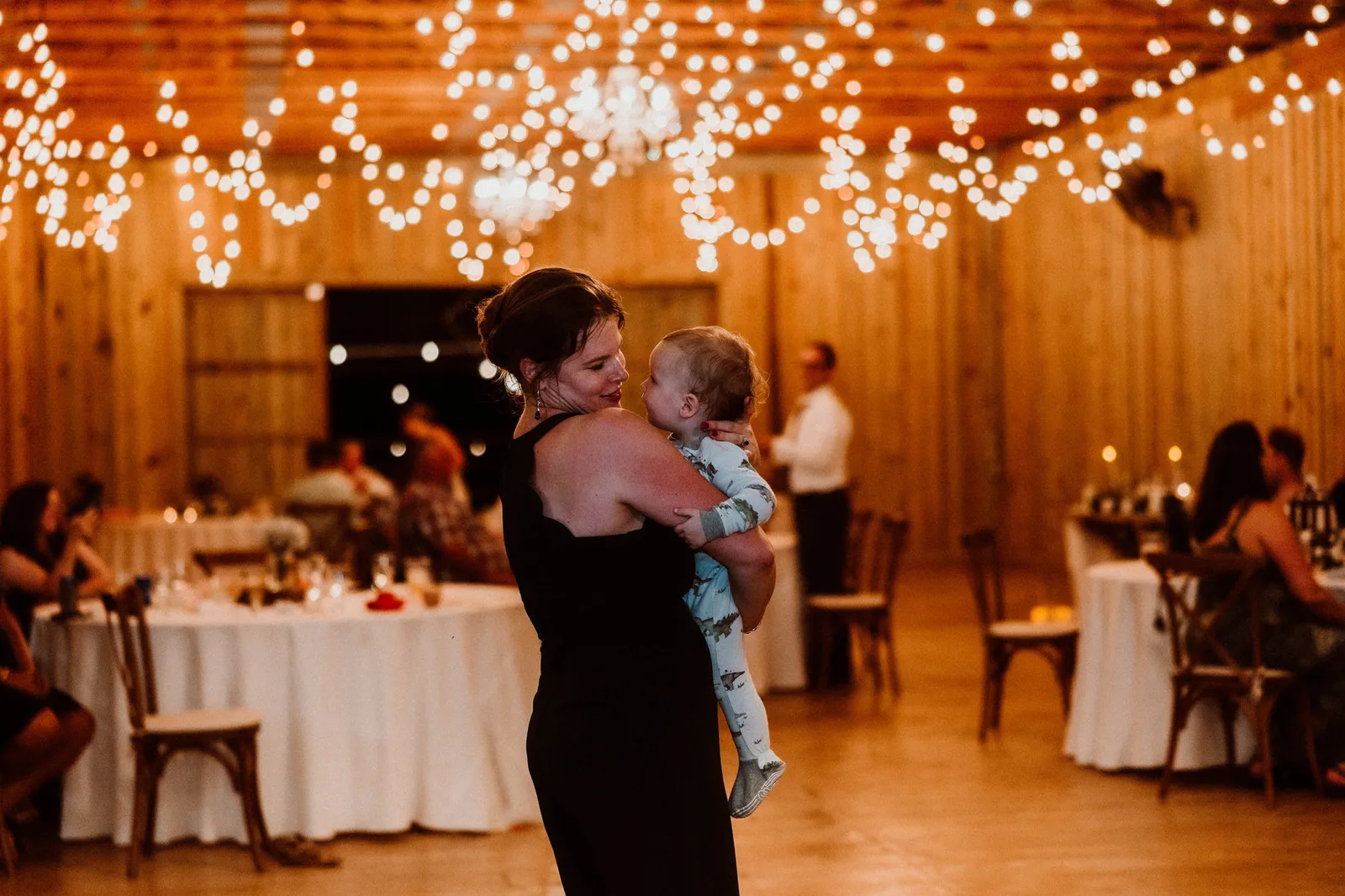 Woman in a black dress dancing with a baby in her arms