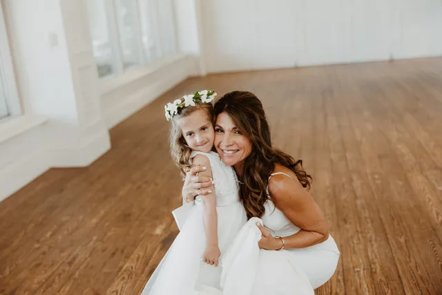 Bride crouching to hug her flower girl