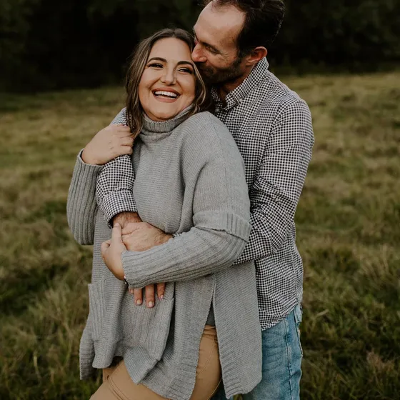 Nikki Seiler laughing as her husband Brian hugs her from behind